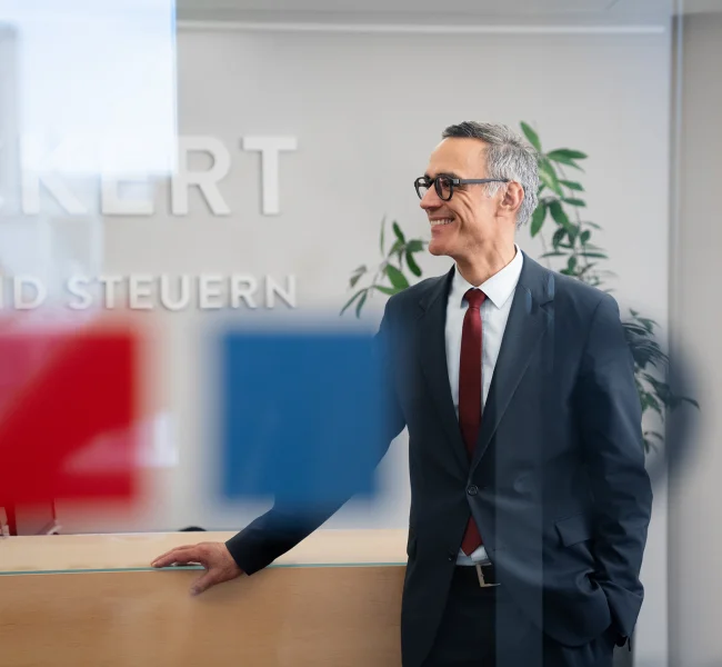 Rechtsanwalt der Kanzlei Dieckert Recht und Steuern steht lächelnd an der Rezeption im Büro Berlin